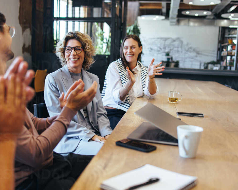 Happy business people applauding during a meeting in an office. Business colleagues celebrating success in a boardroom. Team of professionals working together in a startup.
